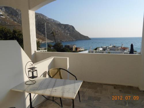 a table and chair on a balcony with a view of the ocean at Alkyonis Apartments in Panormos Kalymnos