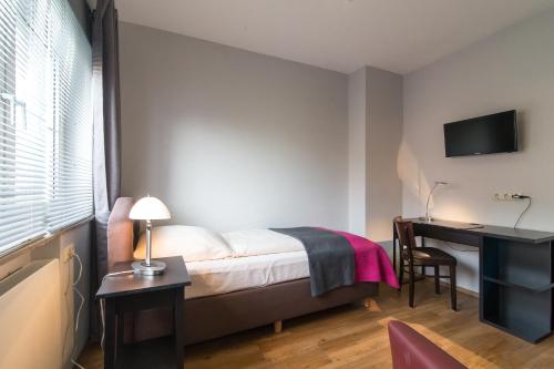 a bedroom with a bed and a desk with a computer at Hotel Klein Frankfurt in Frankfurt/Main