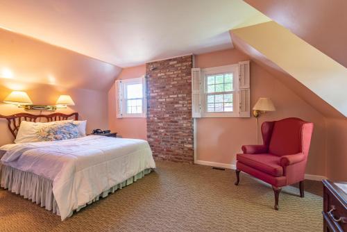 sypialnia z łóżkiem i czerwonym krzesłem w obiekcie Century Suites Hotel w mieście Bloomington
