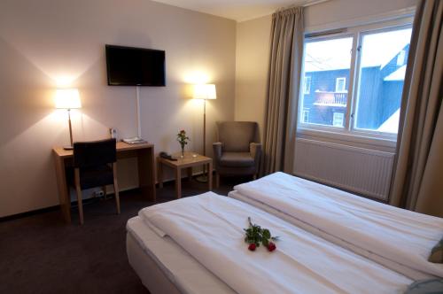 a hotel room with a bed and a desk and a window at Bergstadens Hotel & Spa in Røros