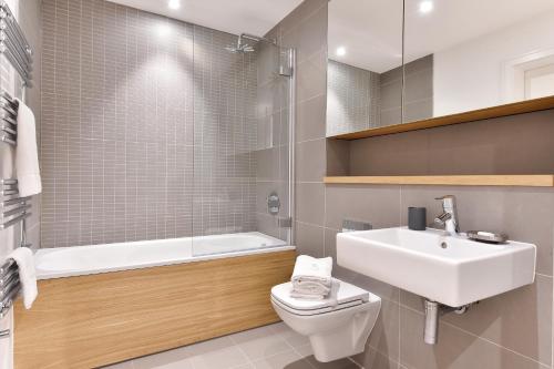 La salle de bains est pourvue d'un lavabo, de toilettes et d'une baignoire. dans l'établissement Shoreditch London Apartments, à Londres