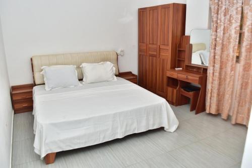 um quarto com uma cama, uma cómoda e um espelho em E3G Sarl em Lomé