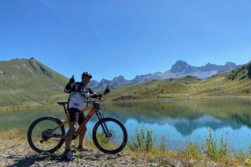 a man standing next to a bike next to a lake at CHALET LYOBA in Le Grand-Bornand