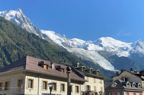 a building with snow covered mountains in the background at CHALET LYOBA in Le Grand-Bornand