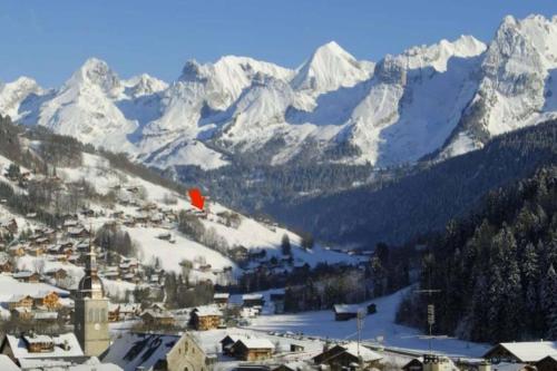 a town in the snow with mountains in the background at CHALET LYOBA in Le Grand-Bornand
