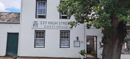 a white house with a tree in front of it at 137 High Street Guest House in Grahamstown