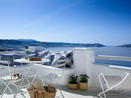 a balcony with chairs and a table and a view of the water at Rocabella Mykonos Hotel in Agios Stefanos