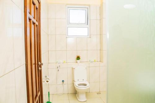 a bathroom with a toilet and a window at EMIRATES REEF APARTMENT 8D in Mombasa
