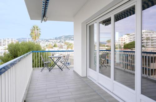 einen Balkon mit Glastüren und einem Tisch mit Stühlen in der Unterkunft 2BDR Reine Astrid in Cannes