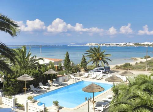 uma piscina com cadeiras e guarda-sóis ao lado de uma praia em Hotel Lago Dorado - Formentera Break em La Savina