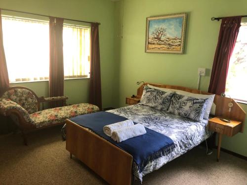 a bedroom with a bed and a chair and windows at DKC Accommodation in Sutherland