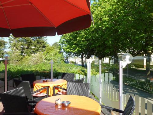 een terras met tafels, stoelen en een parasol bij Apartementhäuser Marlene & Olivia in Juliusruh