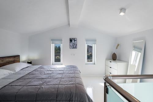 a white bedroom with a bed and two windows at ASTERIA PEARL VILLA 2 with Rooftop Jacuzzi in Tigaki