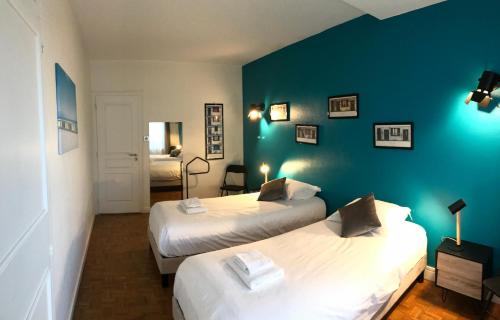 Un dormitorio con dos camas y una pared azul. en LA FORCLAZ - Centre ville & Lac, Balcon, Parking, en Annecy