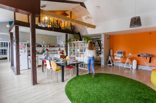 a woman walking around a room with a green rug at Smile Hostel in Nizhny Novgorod