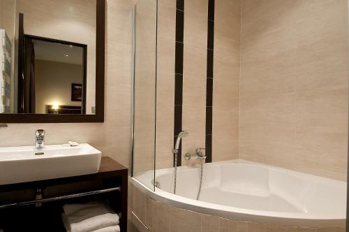 a bathroom with a sink and a bath tub at Hotel Choiseul Opera in Paris