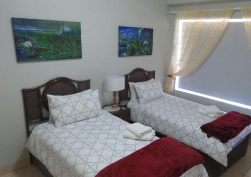 1 dormitorio con 2 camas y ventana en Adagio Luxury Self Catering, en Stilbaai