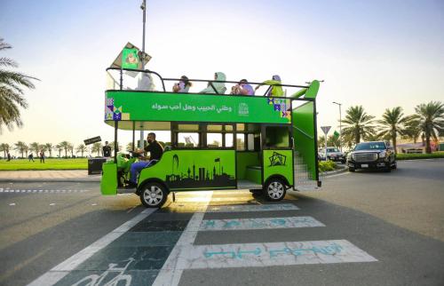 a green double decker bus driving down a street at Bay La Sun Hotel and Marina - Emaar King Abdullah Economic City in King Abdullah Economic City