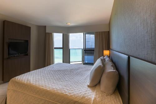 a bedroom with a large bed with a large window at Transamerica Prestige Recife - Boa Viagem in Recife