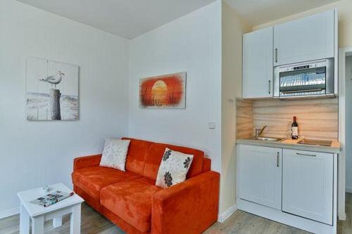 ヴェニングシュテットにあるApp-7-in-strandnaher-Lage-Baederstil-Villa-in-Wenningstedt-Syltのリビングルーム(オレンジ色のソファ付)、キッチンが備わります。