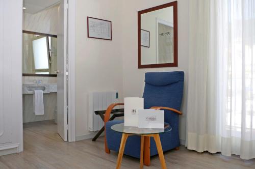 a living room with a blue chair and a table at Hotel Llafranch in Llafranc