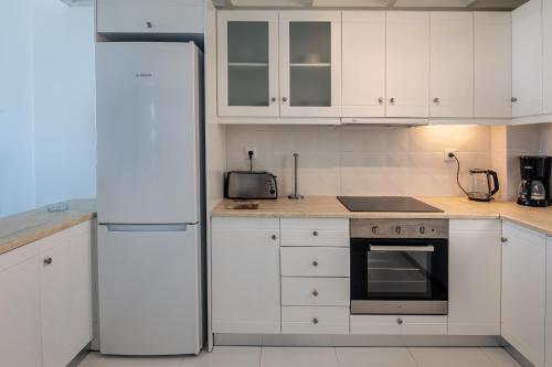 a kitchen with white cabinets and a white refrigerator at ASTERIA PEARL VILLA 2 with Rooftop Jacuzzi in Tigaki