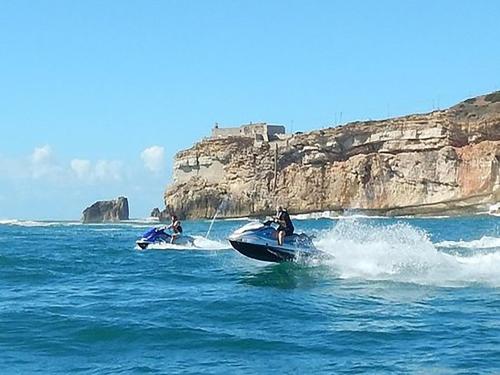 two people riding on jet skis in the ocean at Hotel Mare in Nazaré
