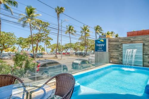 a swimming pool with chairs next to a building at Happy Hotel Pajuçara in Maceió