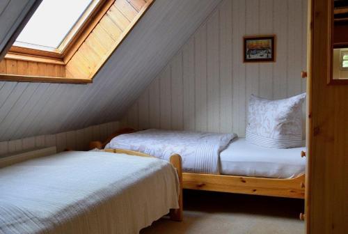 a attic bedroom with two beds and a window at Ferienhof-Heidemann in Neustadt am Rübenberge