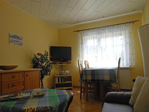 a living room with a table and a television at Bungalow-Lerchennest in Wittdün