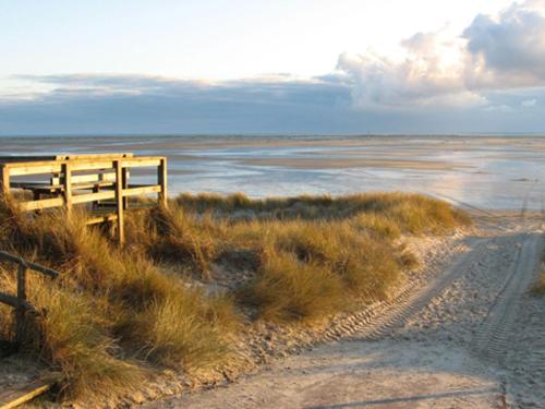 a dirt road next to a beach with the ocean at Bungalow-Lerchennest in Wittdün