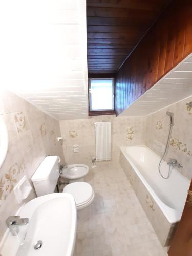 une salle de bain avec toilettes, lavabo et baignoire dans l'établissement Ampia Mansarda a Dimaro in Val di Sole, à Monclassico