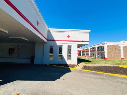 a large white building with a red stripe on it at Traveler's Place Inn & Suites in Scottsboro