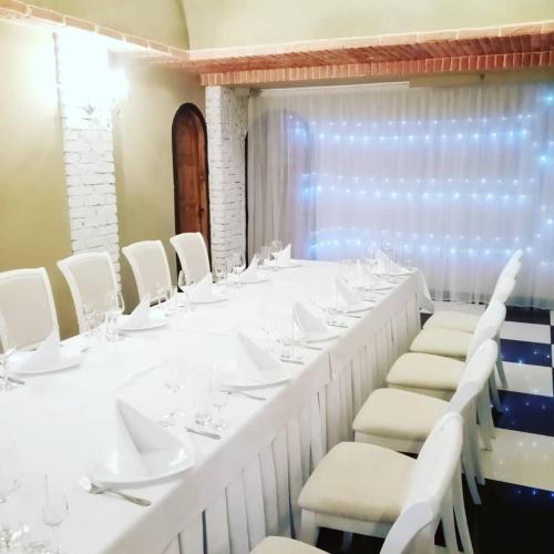 a long white table with white chairs and wine glasses at Medzhybozhskiy Zamok in Tribukhovtsy