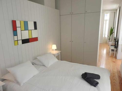 una camera da letto con un letto bianco con una borsa nera sopra di Oporto Delight 1 Luxury Apartment in Historic Center with Balcony Max 4 p a Porto