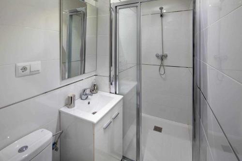 y baño blanco con lavabo y ducha. en Wanderlust Malaga Apartamentos 2, en Málaga