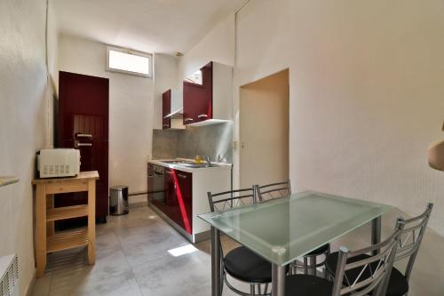 une petite cuisine avec une table en verre et une cuisinière dans l'établissement Appartements des Teinturiers, à Avignon