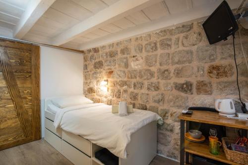 a bedroom with a bed and a stone wall at Private Accomodation Linda in Dubrovnik