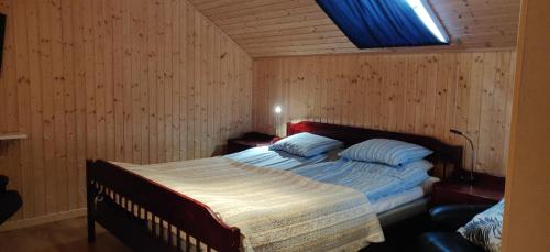 ein Schlafzimmer mit einem Bett in einem Zimmer mit Holzwänden in der Unterkunft Lilla lägenheten Västra Karstorp in Aneby