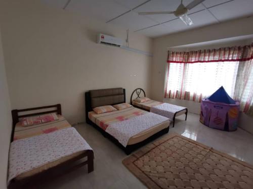 a bedroom with three beds and a ceiling fan at Villa Pulai Indah Temerloh in Temerloh