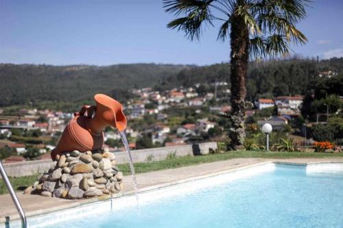 a statue of a dog with a hat sitting next to a swimming pool at Casa Rural do Salgueirinho in Santo Tirso