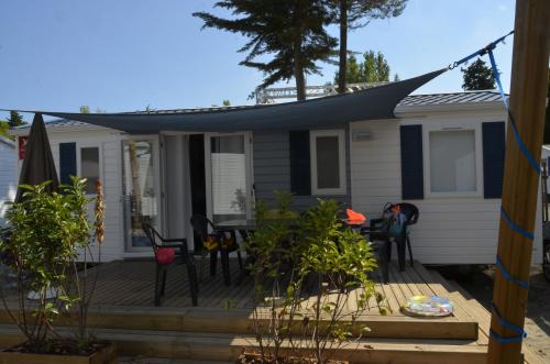 a house with a deck with chairs and an umbrella at Maïana Resort in La Grande-Motte