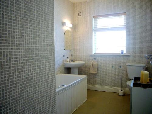 a bathroom with a tub and a sink and a toilet at Dacha Holiday Home by Trident Holiday Homes in Ardmore