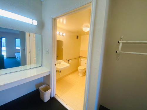 a bathroom with a sink and a toilet and a mirror at Traveler's Place Inn & Suites in Scottsboro