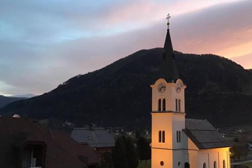 a church with a clock tower with a mountain in the background at WIEDWEG GOLD in Wiedweg