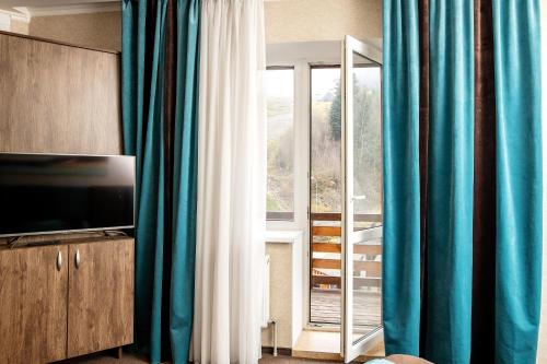 バコヴェルにあるPrivate Rooms in Hotel Lift 1Rの青いカーテン、テレビ、窓が備わる客室です。