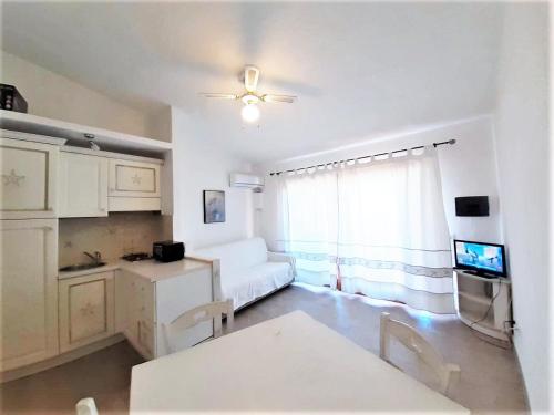 sala de estar blanca con sofá y ventana en Marineledda Apartments, en Golfo Aranci