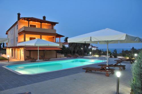 a swimming pool with two umbrellas and a house at Achladi Beach in Achladi