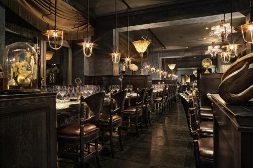 a restaurant with a bar with chairs and chandeliers at Stora Hotellet; BW Premier Collection in Umeå