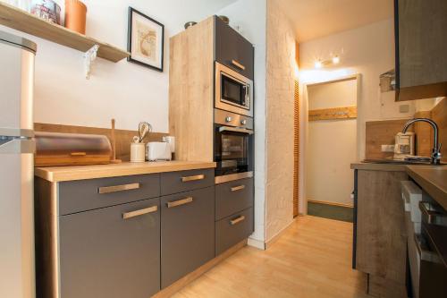 a kitchen with gray cabinets and a microwave at Apartment Peacock - Steinbock Lodges in Zell am See